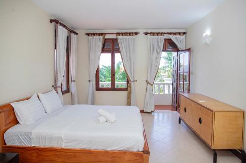 una camera da letto con un grande letto con lenzuola bianche e finestre di Green Villa Hồ Bơi riêng a Phan Thiet