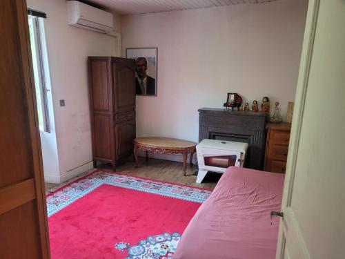 une chambre avec un lit, une commode et un tapis rose dans l'établissement Chambre chez l'habitant, à Livinhac-le-Haut