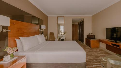 a bedroom with a large white bed and a television at InterContinental Brisbane by IHG in Brisbane