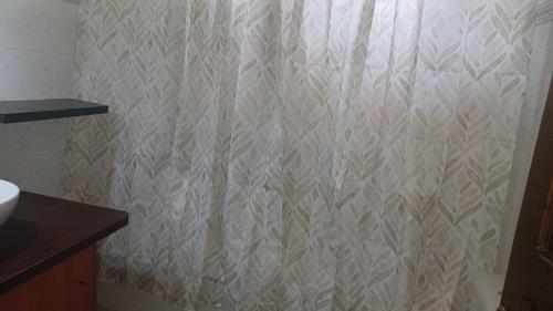 a white shower curtain in a bathroom with a sink at family home in Kanálion