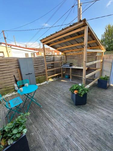 un patio avec une pergola en bois et une table et des chaises dans l'établissement Bella casita, à Dunkerque