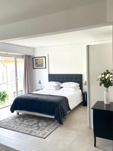 - une chambre avec un grand lit et un vase de fleurs dans l'établissement Suite élégante et moderne Cannes centre, à Cannes