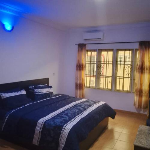 a bedroom with a bed and two windows at Peace in Lekki