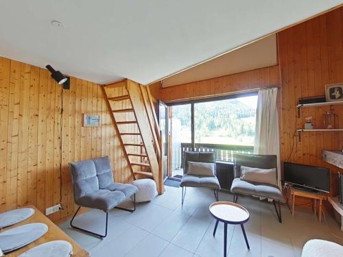 un salon avec un escalier, des chaises et une télévision dans l'établissement Appartement cosy avec cheminée et balcon, 6 couchages, Le Grand-Bornand - FR-1-241-63, au Grand-Bornand
