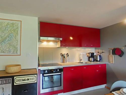 une cuisine avec des armoires rouges et un évier dans l'établissement Appartement cosy avec cheminée et balcon, 6 couchages, Le Grand-Bornand - FR-1-241-63, au Grand-Bornand