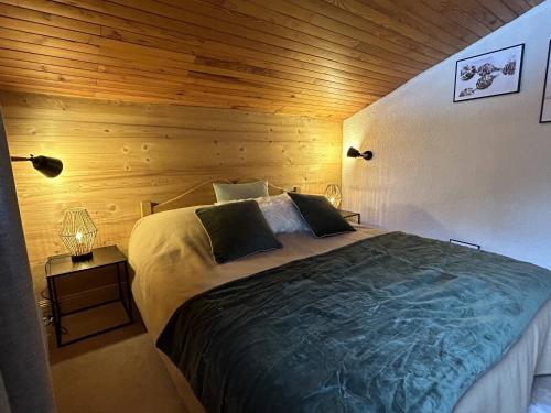 une chambre avec un grand lit avec un mur en bois dans l'établissement Duplex skis aux pieds avec bureau, wifi et TV grand écran - FR-1-355-252, à Les Allues