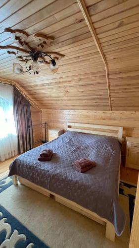 a bed in a wooden room with a ceiling at Elizabeth in Mykulychyn