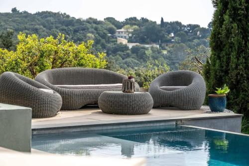 - un groupe de chaises en osier assis à côté d'une piscine dans l'établissement Magnifique villa avec piscine, à Biot