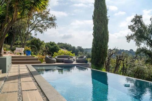 une piscine avec des chaises longues et des arbres dans l'établissement Magnifique villa avec piscine, à Biot