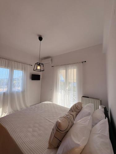 a white bedroom with a large bed with white pillows at Irène House in Egina