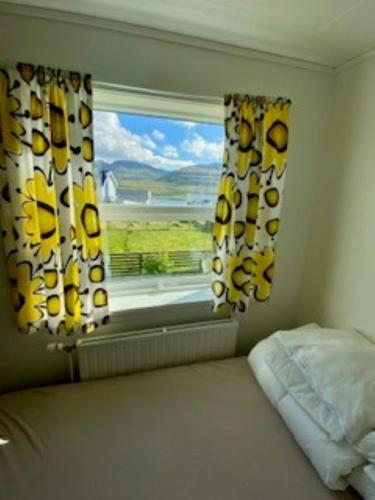a bedroom with a bed and a window with a view at Nice one-story house in Suduroy in Tvøroyri