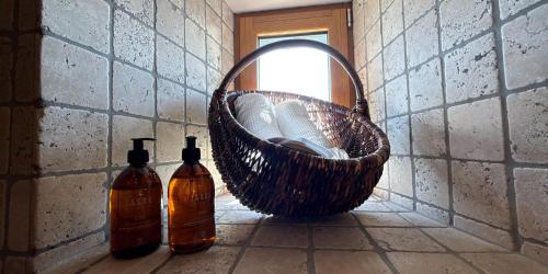 a basket on a wall with a mirror and two bottles at Manoir Des Douets Fleuris in Cancale