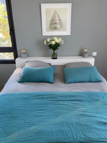 un lit avec deux oreillers bleus et un vase de fleurs dans l'établissement Magnifique villa Quartier Benoît, 200m de la plage, à La Baule