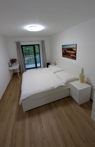 a white bedroom with a large bed and a window at JASMIN HOME Apartments in Vítkovice