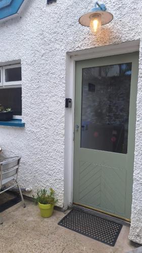 a green garage door on a white building with a bench at Ballycastle Town Centre Apartment in Ballycastle