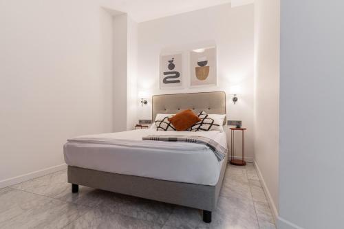 a white bedroom with a bed with two pillows at H11 Aparthotel in Kraków