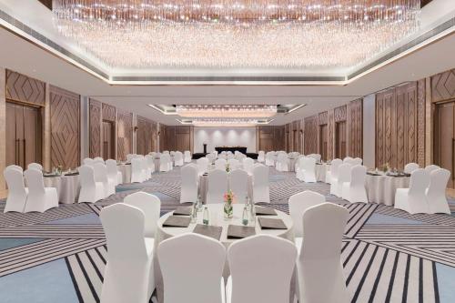 a banquet hall with white chairs and tables and a chandelier at Crowne Plaza Lucknow by IHG in Lucknow