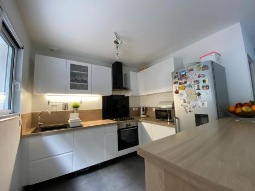  La cuisine est équipée de placards blancs et d'un réfrigérateur. dans l'établissement Maison familiale proche de paris, à Bagneux