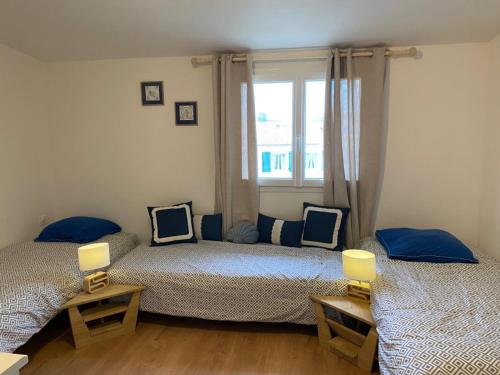 deux lits dans une chambre avec une fenêtre dans l'établissement L'Olivière, à Fouras