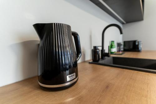a black coffee pot sitting on a wooden table at H11 Aparthotel in Kraków