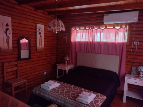 a bedroom with a bed and a window with pink curtains at cabaña la casa del arbol in Tandil
