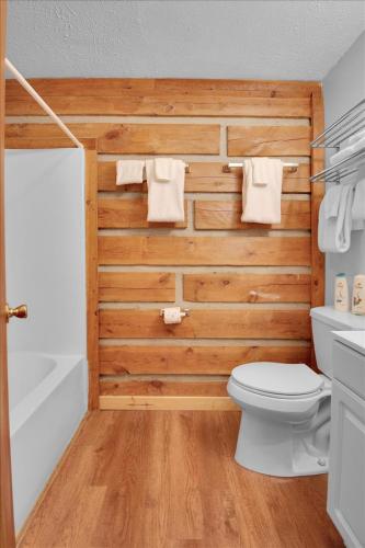 a bathroom with a wooden wall with a toilet and a tub at Cozy Log Cabin Retreat in Tennessee in Pigeon Forge