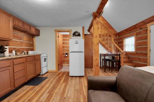 a kitchen with a white refrigerator and a table at Cozy Log Cabin Retreat in Tennessee in Pigeon Forge