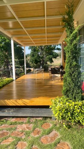 a porch with a wooden deck with a table at บ้านไร่ฟ้าสวยวังน้ำเขียว Nordic 01 in Ban Kom