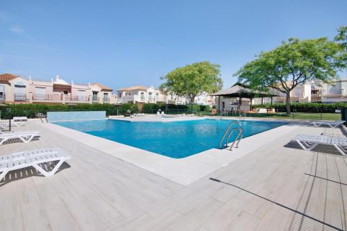 a swimming pool with two white benches next to at Estrella in Ayamonte