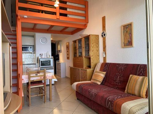 un salon avec un canapé rouge et une cuisine dans l'établissement SP150-015 Appartement studio mezzanine 3 couchages SAINT PIERRE LA MER, à Saint Pierre La Mer