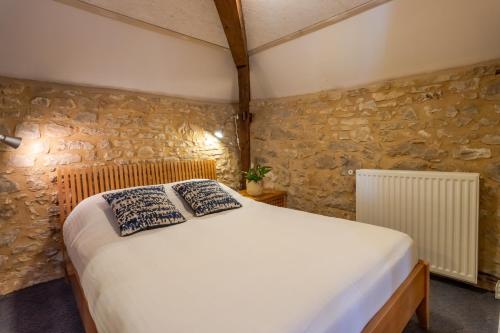 a bed in a room with a stone wall at Maison Salle de Musique in La Forge-dʼAns