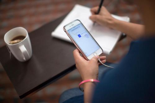 a person sitting at a table holding a cell phone at Holiday Inn Express London Victoria by IHG in London