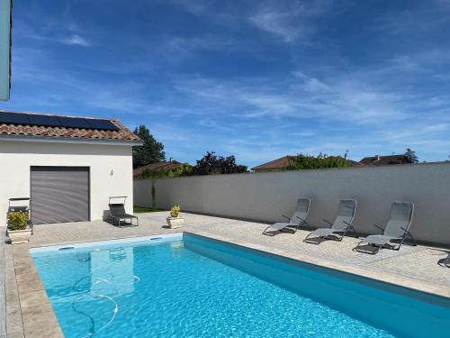 - une piscine avec quatre chaises à côté d'un bâtiment dans l'établissement Les Chanterelles, à Crêches-sur-Saône