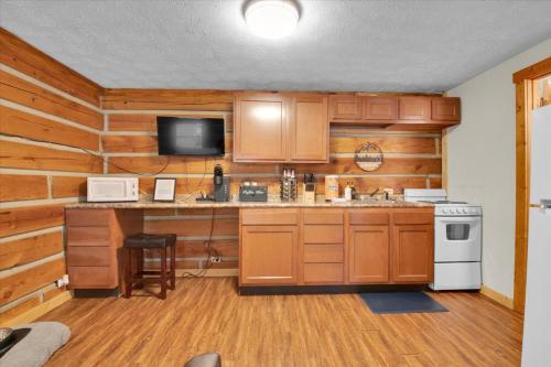 a kitchen with wooden cabinets and a counter with a microwave at Studio Cabin with Loft near Smoky Mountains in Pigeon Forge