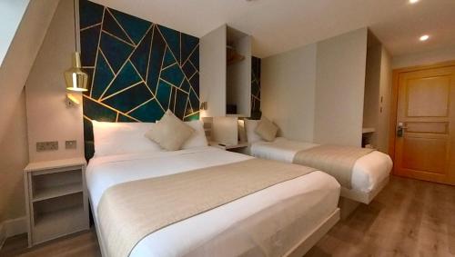 a hotel room with two beds and a wall at NOX Olympia in London