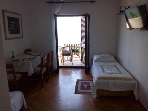 a room with two beds and a dining room with a table at Villa Milas - Apartman 04 in Tkon