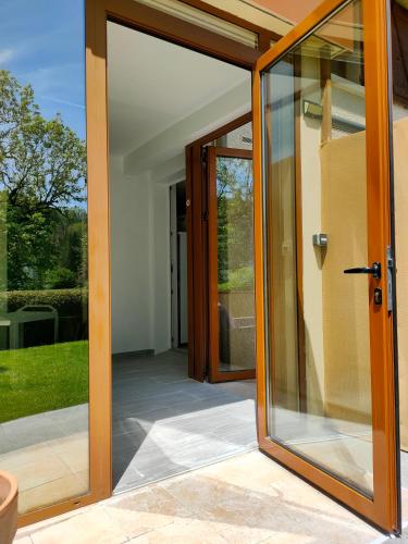 an open glass door of a house with a patio at Gîte 829 Montagnes du Jura avec Spa et Sauna classé 3 étoiles in Foncine-le-Haut