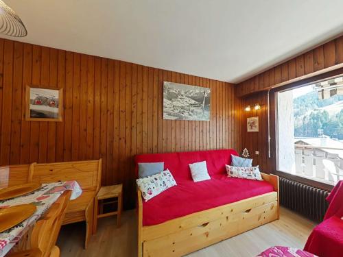 - une chambre avec un lit rouge et une fenêtre dans l'établissement Studio 4 pers, centre village, proche commerces et pistes, TV incluse - FR-1-241-29, au Grand-Bornand