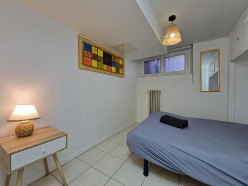 une chambre avec un lit et une table avec une lampe dans l'établissement Secret de Richebourg - Cœur du Mans - 4pers, au Mans