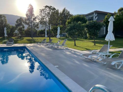 a swimming pool with chairs and umbrellas at Alegria Kefalonia in Katelios