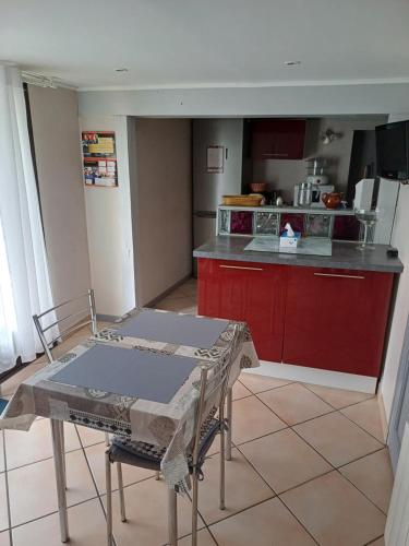 - une cuisine avec des placards rouges et une table dans une pièce dans l'établissement La Calenderie, à Bouquetot