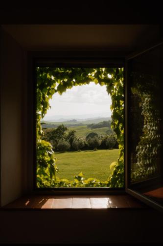 a window with a view of a green field at Podere la Piscina RestArt in San Casciano dei Bagni