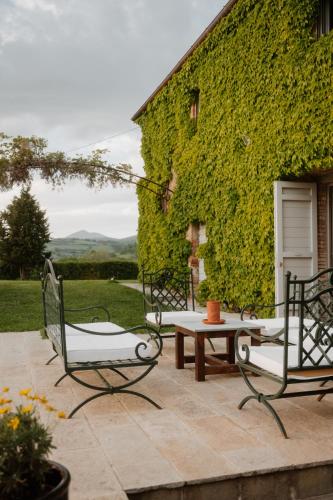 a patio with two chairs and a table and a building at Podere la Piscina RestArt in San Casciano dei Bagni