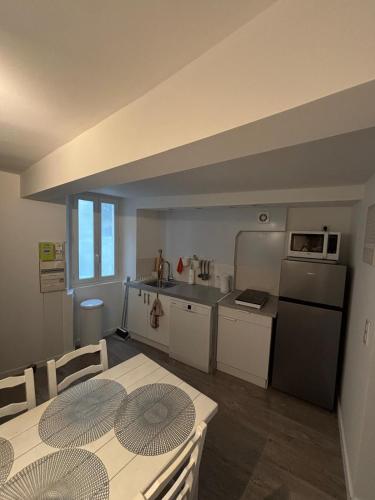 une cuisine avec une table, des chaises et un réfrigérateur dans l'établissement le minicoulier, à Carros