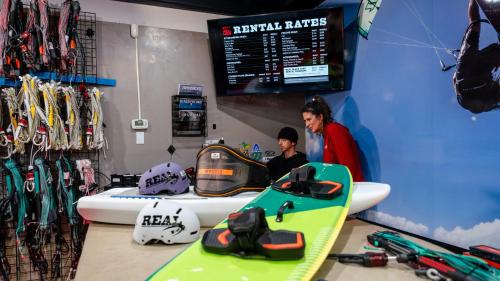 a man and a woman standing in a room with a snowboard at Buxton Slick - Waterfront 2-Bedroom, 2-Bathroom Suite at REAL Watersports in Waves