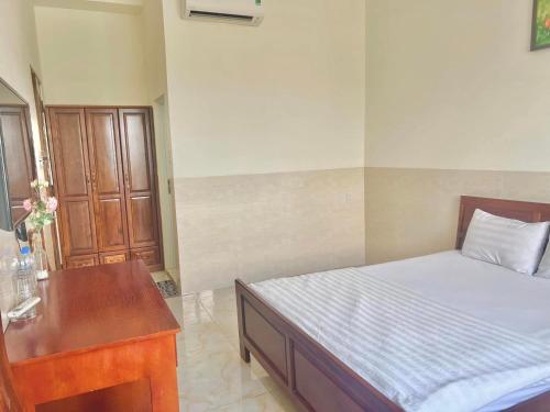 a bedroom with a bed and a wooden desk at Magnolia Hotel Cam Ranh in Cam Ranh