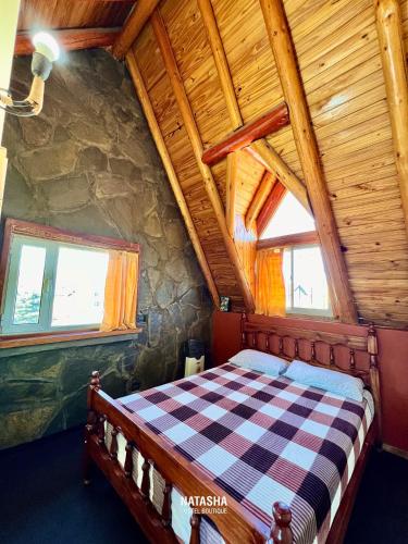 Un dormitorio con una cama en una cabaña de troncos en Natasha Hostel Boutique, en Caviahue