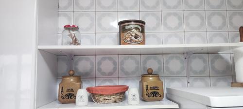 a kitchen shelf with jars and a sink at Rosalia Rooms in A Estrada