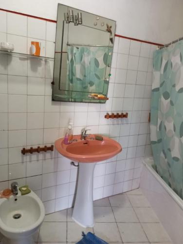 a bathroom with a sink and a mirror and a toilet at Quarto da casa da avó in Cercal
