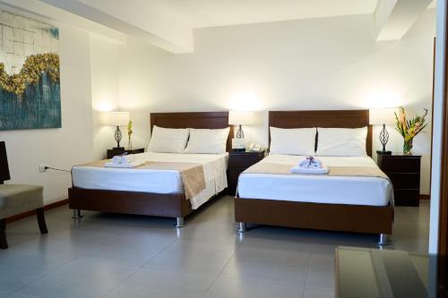 a bedroom with two beds and a table and a couch at Hotel Marcoantonio - Moyobamba in Moyobamba